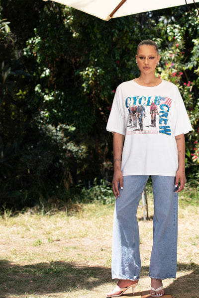 Model in Cycle Crew Embellished Tee in front of bushes, highlighting its relaxed fit and crystal-enhanced graphic.