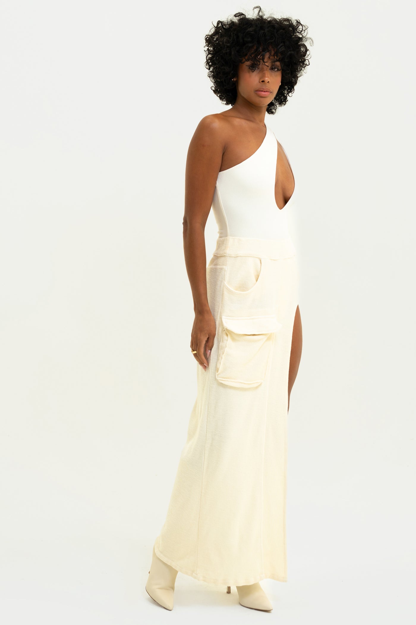 Model showcasing the White Aspen Cargo Skirt with unique cargo pocket, high leg slit, in comfortable corded terry.