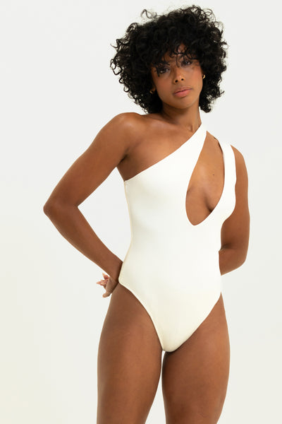 Fitness model showcasing the Vintage Souls Elegant Winter White Asymmetrical Bodysuit.